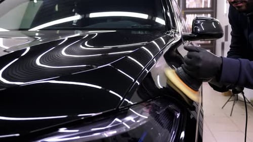 Man Polishing a Black Car in Auto Shop