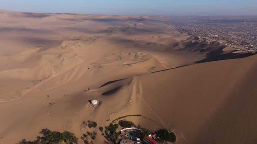 Pullback over Desert Ridges Surrounding Huacachina Oasis, Buildings ...