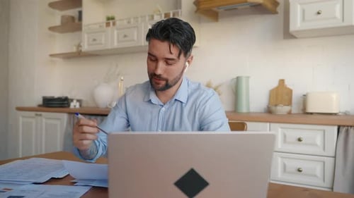 Man Working on Laptop at Kitchen Table