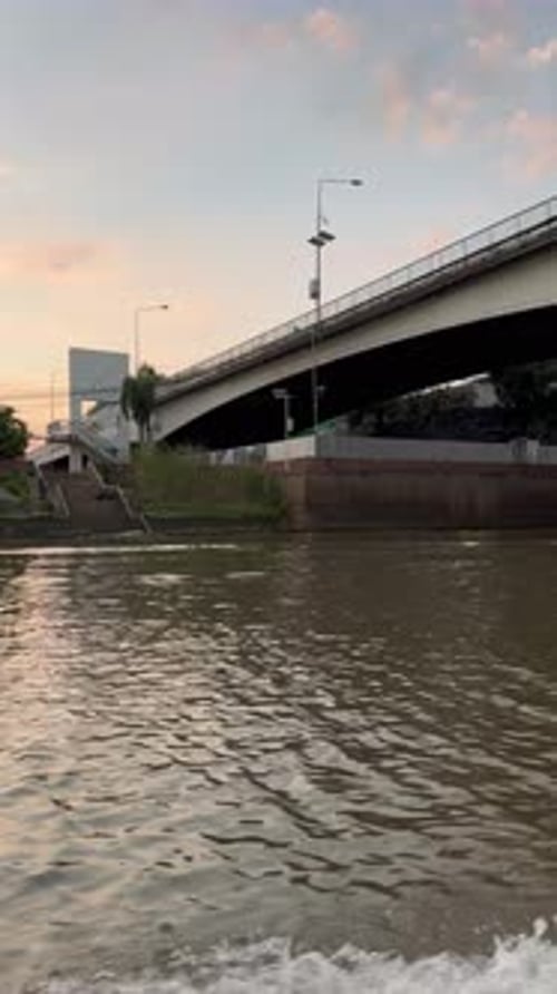 Vertical Video Wooden Boat Navigating on a River Canal in Thailand During Sunset Hour