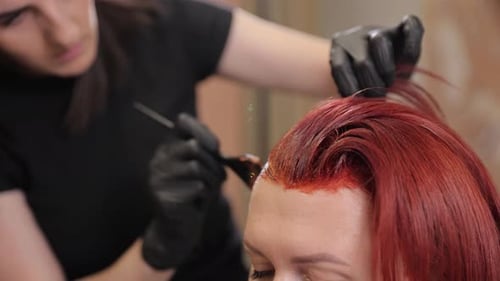 Woman Getting Hair Dyed Vibrant Red by Stylist