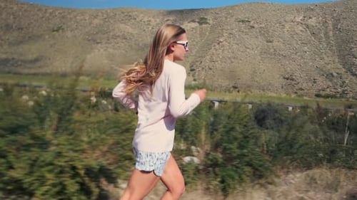 Woman in Sportswear Runs on an Open Road Building Endurance with Mountains