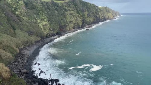 Ocean waves on beautiful black rocks beach. Wild nature green mountains. Shore sea foam blue waves b