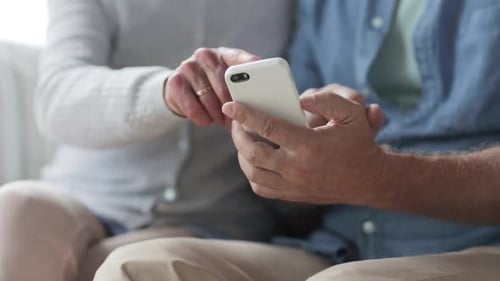 Senior Couple Using Smartphone Device Together Indoors