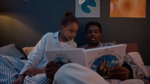 Girl and Man Reading Storybook in Bedroom at Night