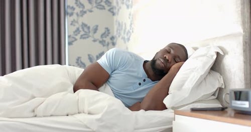 Détente au lit, homme se réveillant dans une chambre confortable avec un éclairage doux