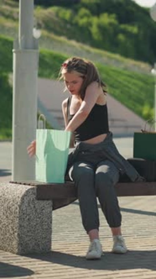 Lady on Bench Sorting Books in Shopping Bags Outdoors