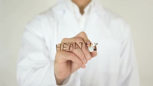 Doctor Writes the Word Healthy on Clear Surface