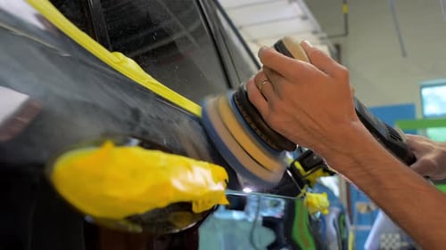 Man Worker Polishing the Car Body in a Auto Body Shop Wide View