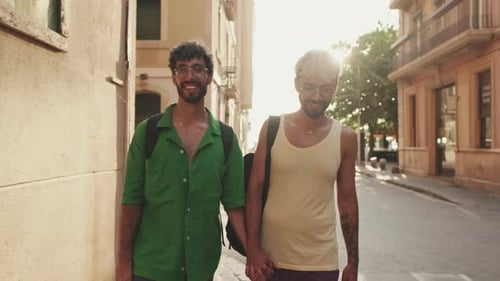 Happy gay tourist couple walking down street holding hands