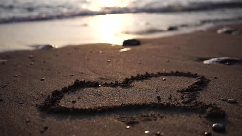 Heart Symbol Drawn on Beach Sand at Beautiful Sunset Washed Away By Sea Waves Hand Drawn Heart on