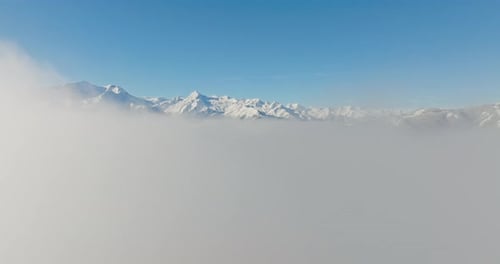 Snowy Mountain Peaks Sticking Above The Clouds
