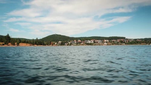 Mountain lake with clear water and green trees and hills on horizon