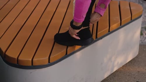 Young Woman Tightening Shoe Laces on Bench