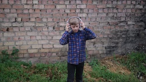 Young Boy Wearing Headphones and Dancing Energetically He's Dressed in a Blue Plaid Shirt and Black