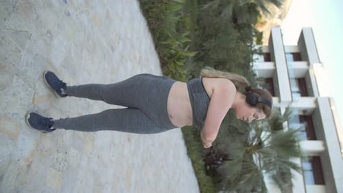 Woman Stretching Arms During Workout in Tropical Setting