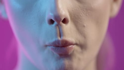 Close Up Of Young Woman's Hand Holding Green Grapes, Mouth Eating The Fruit With Purple Background