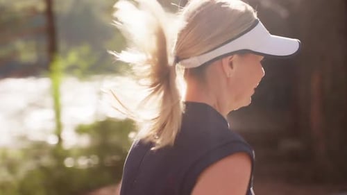 Athletic Woman Jogging on a Sunlit Forest Path