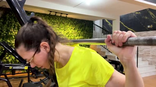 Woman performing squats with a straight bar in gym