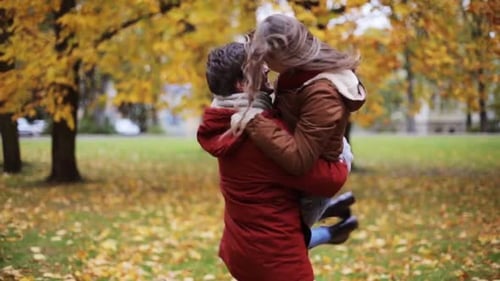 Happy Couple Embracing and Spinning in Autumn Park