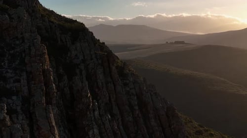Dramatic drone clip of a rocky mountain range with farmlands