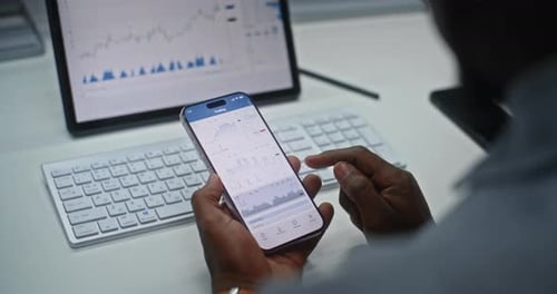 Stock Exchange Trader Analyzing Exchange Market Charts on Smartphone and Tablet Computer