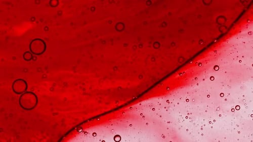 Transparentes rotes kosmetisches Gelfluid mit Seifenblasenöl auf Wasser, weißer farbiger Hintergrund, Makroaufnahme