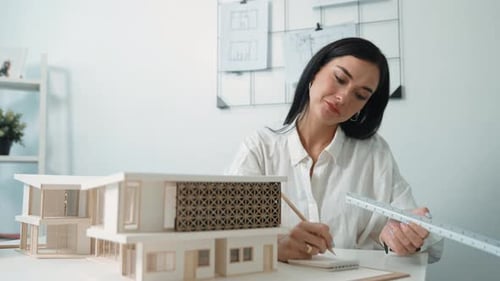 Professional architect using triangular scale measure house model. Immaculate.