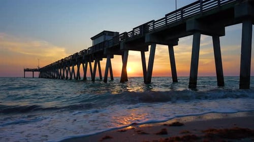 Venice Fishing Pier in Florida at Sunset Evening Seascape with Surf Waves Crashing on Sandy Beach