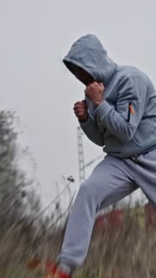 Man Practices Boxing Punches in Rural Grassy Field