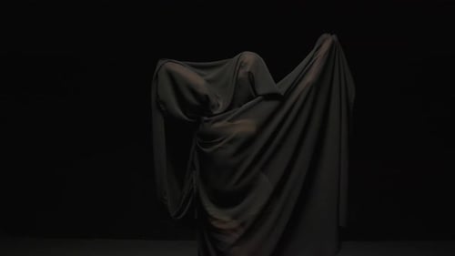 Figure Under Dark Fabric Sheet Against Black Backdrop