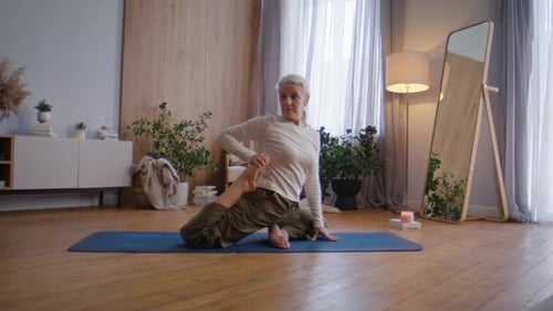 Senior Woman Practicing Yoga on Mat in Living Room