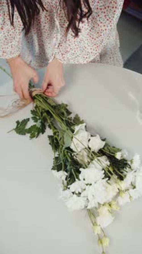 Women's Hands Tie a Bouquet of Flowers Top View Vertical Video