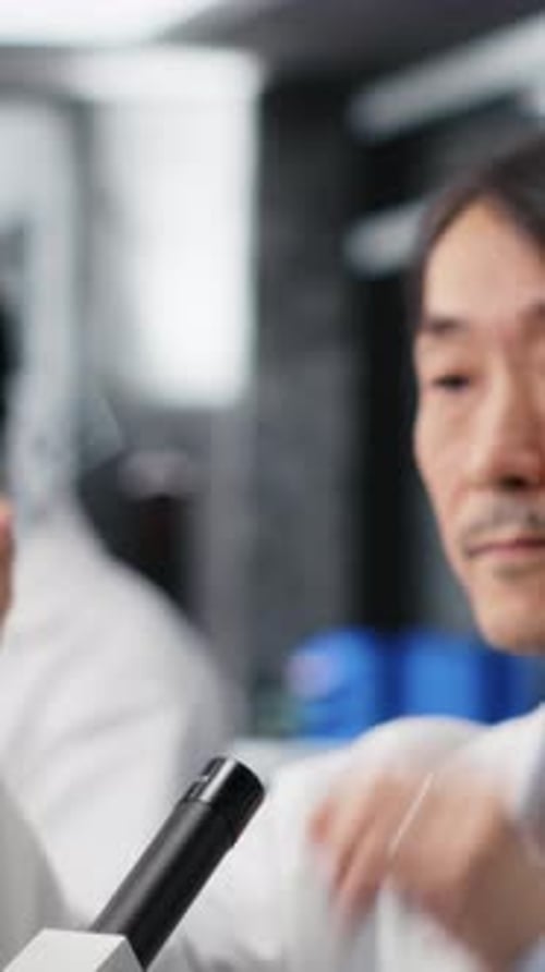 Vertical Video Clinical Microbiologist Examining Microscope Glass Slide in Laboratory to View Cells