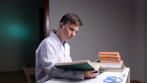 Young Man in Lab Coat Reads Medical Book