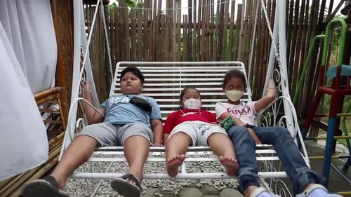 Three Children Relaxing on a Metal Porch Swing