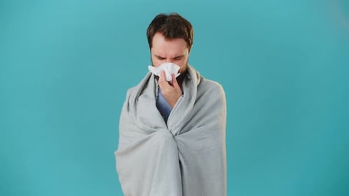Bearded Man Wrapped in Blanket Blowing Nose