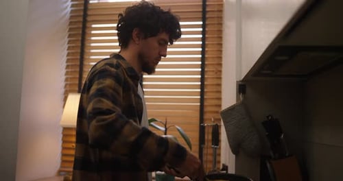 Young Adult Man Cooking Breakfast in Kitchen