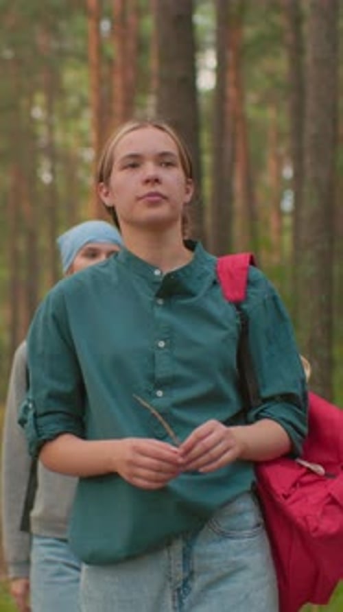 Young Woman Walking Through Peaceful Forest Trail with Red Backpack
