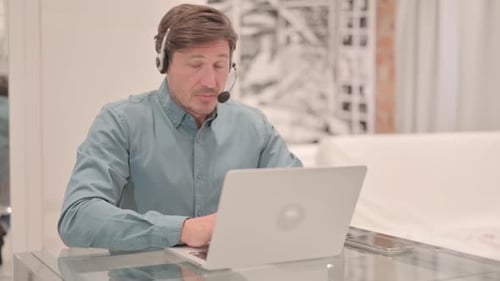Mature Adult Man with Headset Looking toward Camera in Call Center