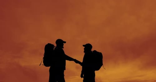 Silhouetted Hikers Fist Bump at Sunset
