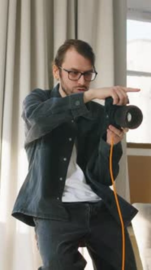 Vertical of Young Male Photographer with Professional Camera Working in Studio