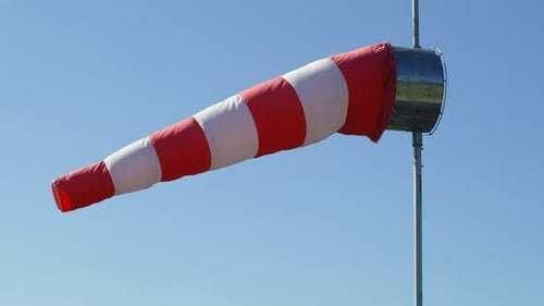 Windsock is waving in the wind against a clear blue sky.