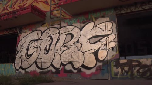 Artista de rua pintando grafite com spray em parede de prédio urbano abandonado