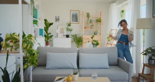 Woman Dances and Waters Plants in Sunny Apartment