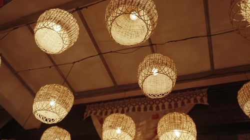 Numerous lamps woven from branches of wicker emit a dim, warm light that bathes everything around.