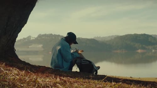 Writing letter by lake in nature, peaceful solo moment in scenic outdoor location