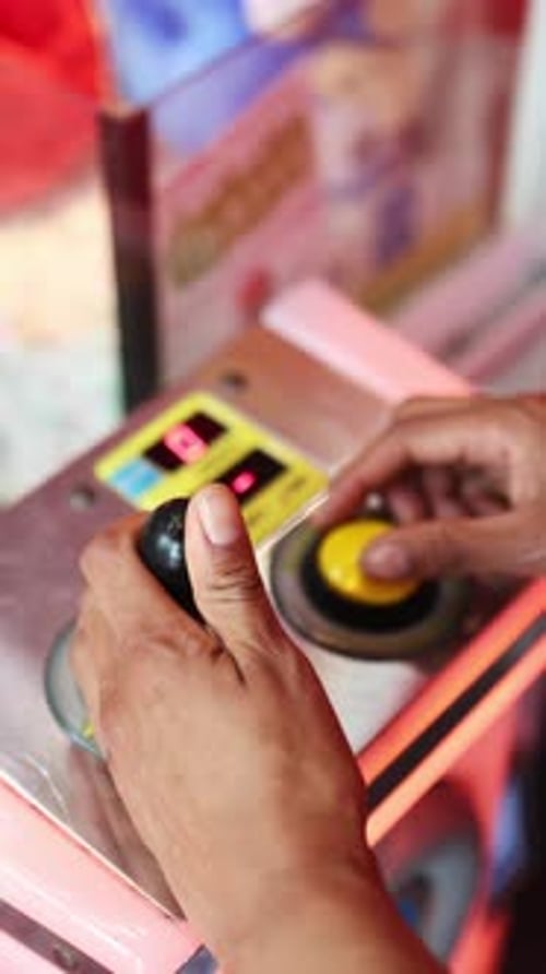 Hands Use Claw Crane Machine at Arcade
