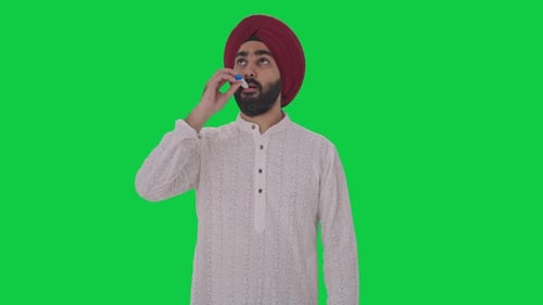 Sick Sikh Indian man measuring fever using thermometer Green screen