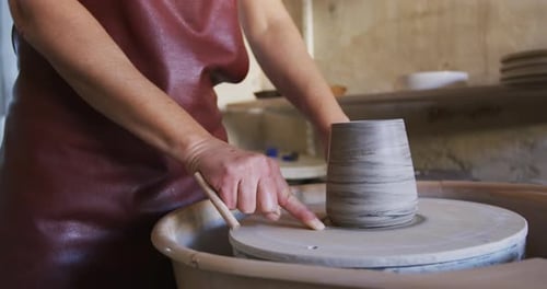 Woman Sitting at a Pottery Wheel in Her Ceramic Studio Shaping A